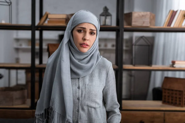 Traurige muslimische Frau im Hidschab blickt im Wohnzimmer in die Kamera, Konzept häuslicher Gewalt — Stockfoto
