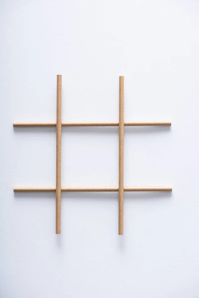 Vue du dessus de la grille en tubes de papier pour tic tac toe game sur surface blanche — Photo de stock