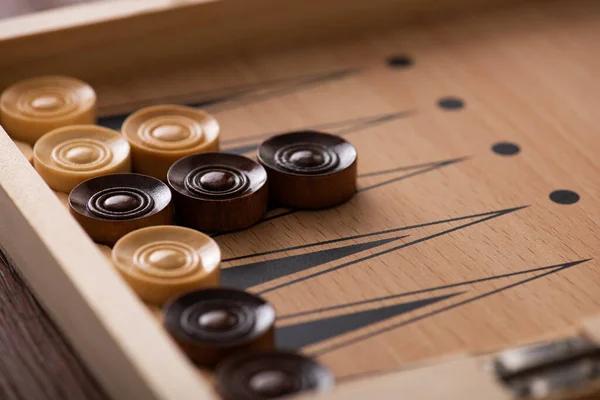 KYIV, UKRAINE - 30 JANVIER 2019 : mise au point sélective des dames en bois sur le plateau de backgammon — Photo de stock