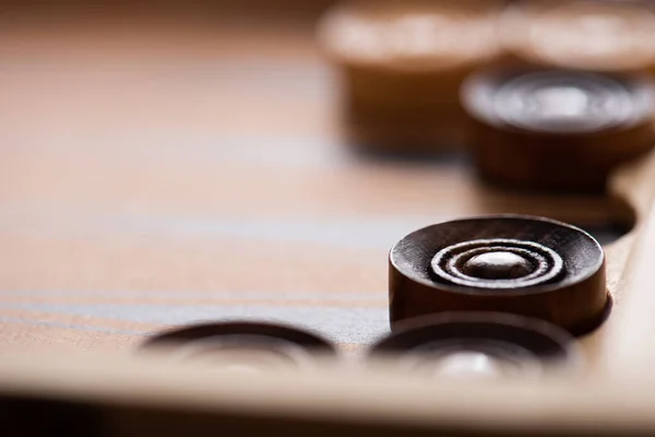 KYIV, UKRAINE - 30 JANVIER 2019 : mise au point sélective des dames en bois sur le plateau de backgammon — Photo de stock