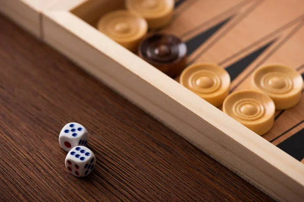 KYIV, UCRANIA - 30 de enero de 2019: pareja de dados en una mesa de madera cerca del tablero de backgammon con damas - foto de stock