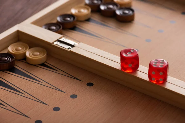 KYIV, UCRANIA - 30 de enero de 2019: enfoque selectivo del par de dados en el tablero de backgammon cerca de las damas - foto de stock