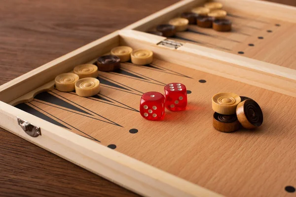 KYIV, UCRANIA - 30 DE ENERO DE 2019: enfoque selectivo del tablero de backgammon con damas y dados en mesa de madera - foto de stock