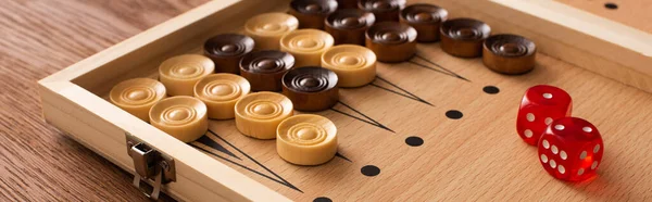 KYIV, UKRAINE - JANUARY 30, 2019: panoramic shot of backgammon board with checkers and dice pair on wooden table — Stock Photo