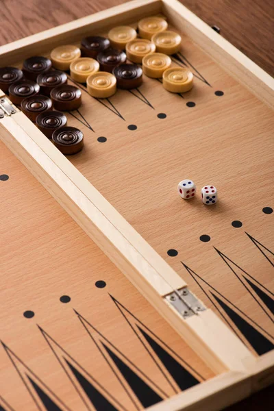 KYIV, UKRAINE - JANUARY 30, 2019: wooden backgammon board with checkers and dice pair on wooden table — Stock Photo