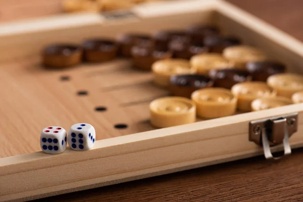 KYIV, UKRAINE - JANUARY 30, 2019: selective focus of dice pair on wooden backgammon board near checkers on wooden table — Stock Photo