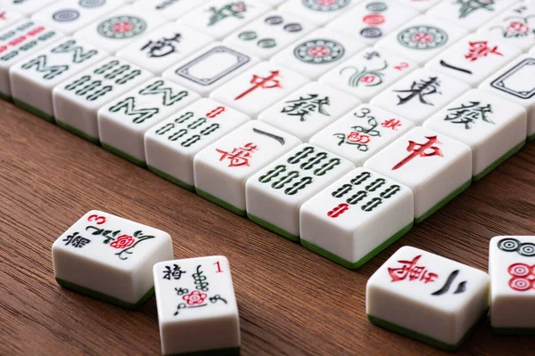 KYIV, UKRAINE - JANUARY 30, 2019: selective focus of field of mahjong game tiles with signs and characters on wooden table — Stock Photo