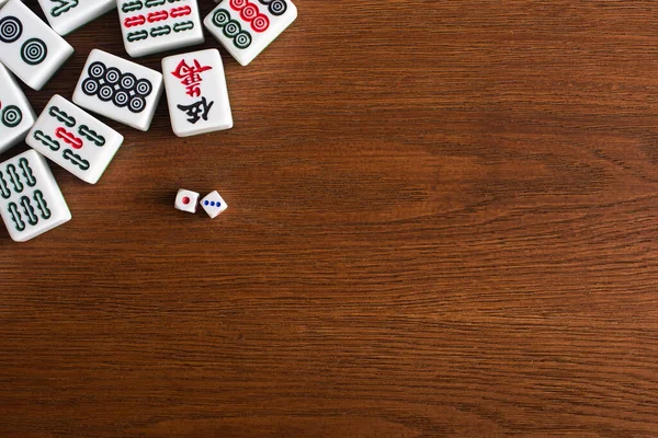 KYIV, UKRAINE - 30 JANVIER 2019 : vue du dessus de la paire de dés près des tuiles de jeu de mahjong sur une table en bois — Photo de stock