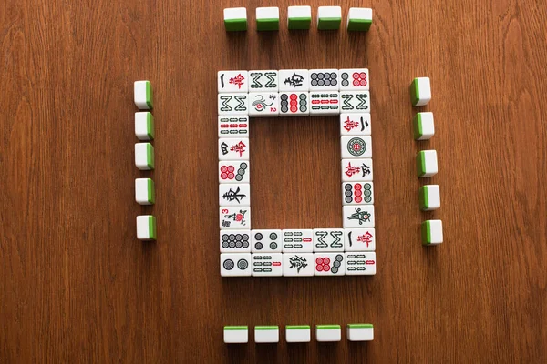 KYIV, UKRAINE - JANUARY 30, 2019: top view of square frame made of mahjong game tiles on wooden table — Stock Photo
