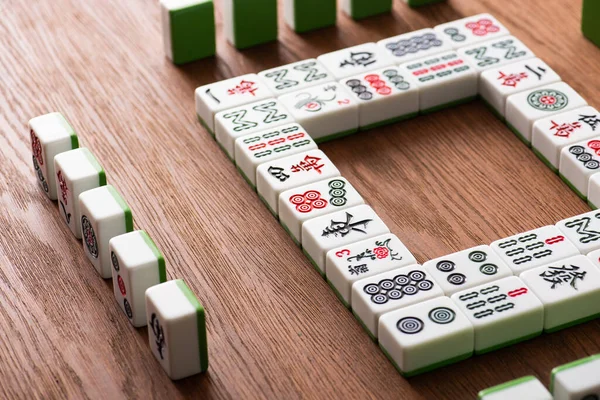 KYIV, UCRANIA - 30 de enero de 2019: marco cuadrado y filas de azulejos de juego de mahjong en la mesa de madera - foto de stock