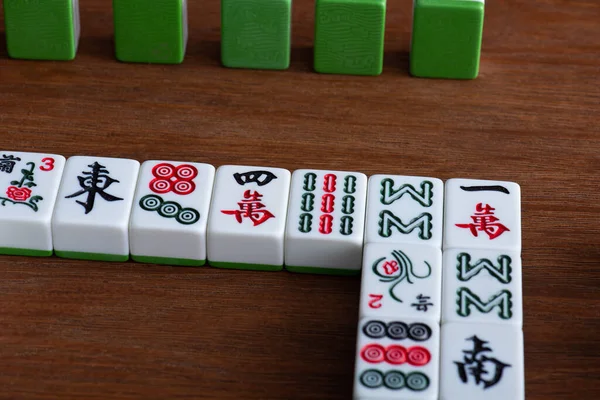 KYIV, UCRANIA - 30 de enero de 2019: fichas de juego de mahjong con signos y personajes en la mesa de madera - foto de stock