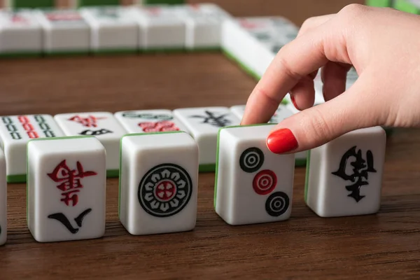 KIEW, UKRAINE - 30. JANUAR 2019: Teilansicht einer Frau, die Mahjong-Spielsteine vom Holztisch nimmt — Stockfoto