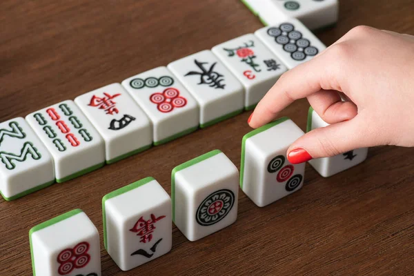 QUIIV, UCRÂNIA - JANEIRO 30, 2019: visão parcial da mulher tomando telha jogo mahjong de mesa de madeira — Fotografia de Stock