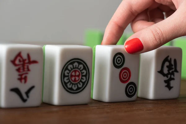 KYIV, UKRAINE - JANUARY 30, 2019: cropped view of woman taking mahjong game tile isolated on grey — Stock Photo