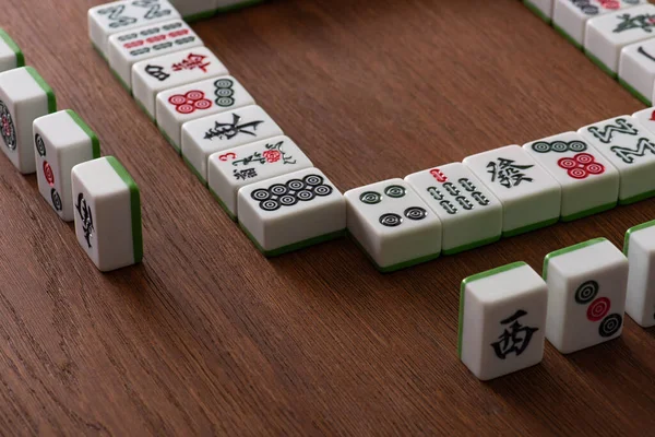KYIV, UCRANIA - 30 de enero de 2019: marco y filas de azulejos de juego de mahjong en la superficie de madera - foto de stock