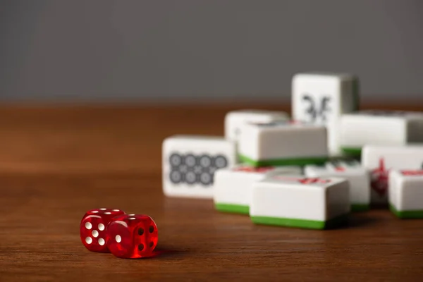 KIEW, UKRAINE - 30. JANUAR 2019: selektiver Fokus des Würfelpaares in der Nähe von Mahjong-Kacheln auf einer auf grau isolierten Holzoberfläche — Stockfoto