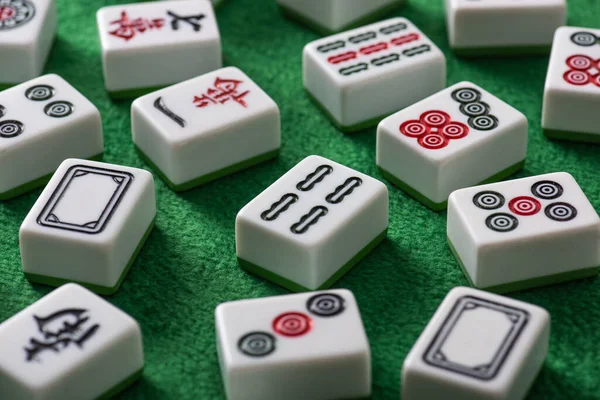 KYIV, UKRAINE - JANEIRO 30, 2019: foco seletivo de azulejos de jogo mahjong brancos com sinais e personagens na superfície de veludo verde — Fotografia de Stock