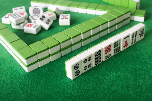 KYIV, UCRANIA - 30 DE ENERO DE 2019: enfoque selectivo de filas y pila de fichas de juego de mahjong en la superficie de terciopelo verde - foto de stock