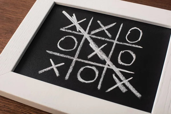 Tic jogo tac toe no quadro negro com cruzou a linha de cruzes na superfície de madeira — Fotografia de Stock