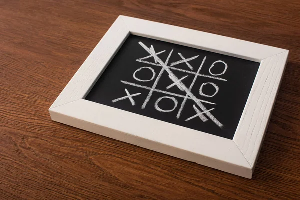 Tic jogo tac toe no quadro negro com cruzou a linha de cruzes na superfície de madeira — Fotografia de Stock