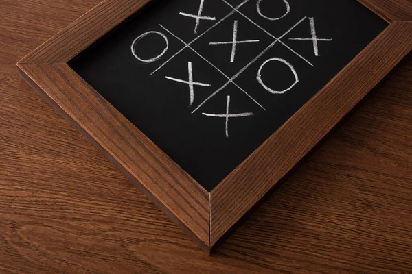 Tic tac toe game on blackboard with chalk grid, naughts and crosses on wooden surface — Stock Photo