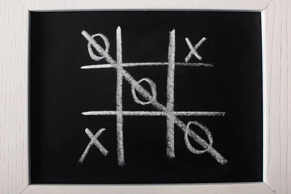 Top view of tic tac toe game on blackboard with crossed out row on naughts — Stock Photo