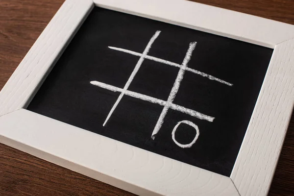 Tic jogo tac toe no quadro negro com grade de giz e nada na superfície de madeira — Fotografia de Stock