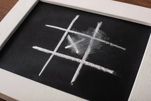 Tic tac toe game on blackboard with chalk grid and cross in center — Stock Photo