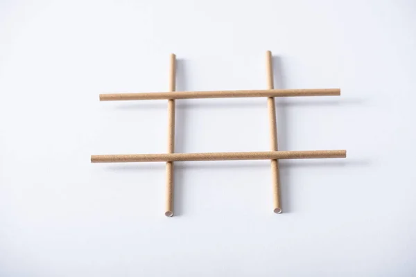Панорамный снимок сетки из бумажных труб для игры в крестики-нолики на белой поверхности — стоковое фото