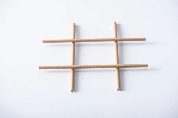 Plano panorámico de rejilla hecha de tubos de papel para tic tac toe juego en la superficie blanca - foto de stock