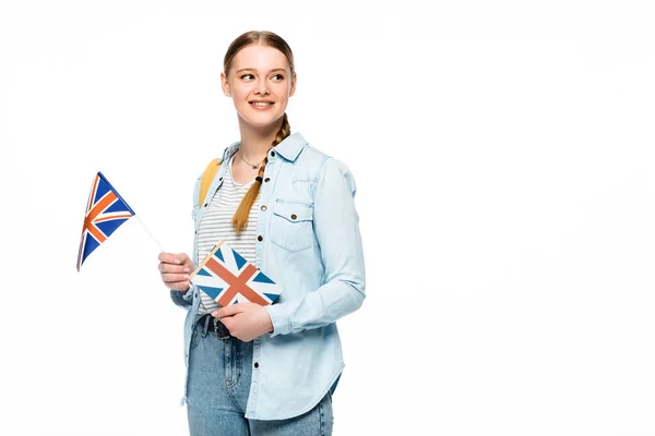 Sonriente bonita estudiante con mochila celebración libro y bandera británica aislado en blanco - foto de stock