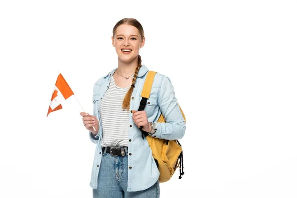 Feliz estudiante bonita con mochila sosteniendo bandera canadiense aislado en blanco - foto de stock