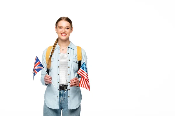 Happy girl with braid and backpack holding flags of america and united kingdom isolated on white — Stock Photo