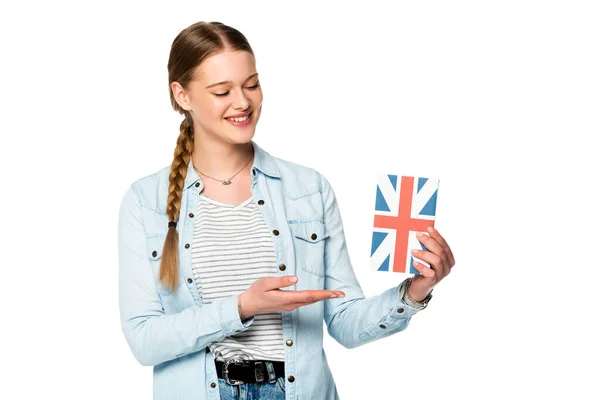 Sorridente bella ragazza con treccia presentando libro con bandiera del Regno Unito isolato su bianco — Foto stock