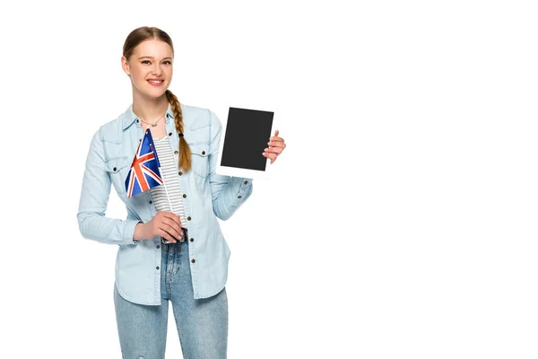 Sonriente chica bonita con trenza sosteniendo tableta digital con pantalla en blanco y bandera del Reino Unido aislado en blanco - foto de stock