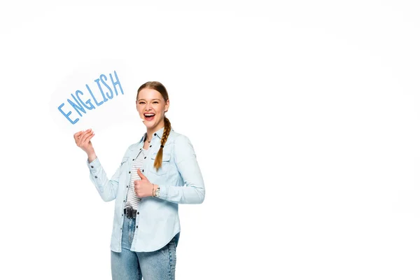 Chica sonriente con trenza sosteniendo la burbuja del habla con letras inglesas y mostrando el pulgar hacia arriba aislado en blanco - foto de stock