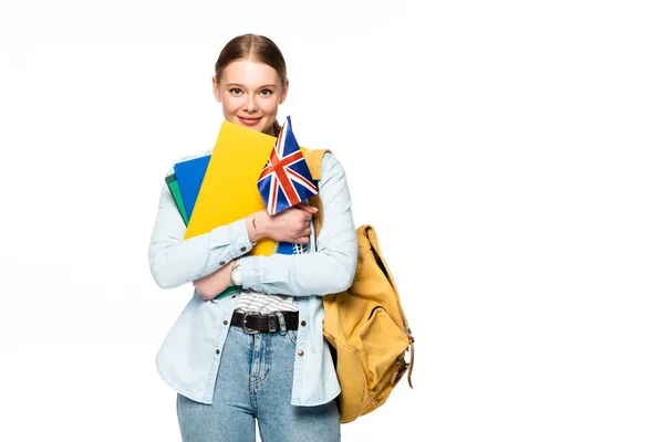Усміхнена дівчина з рюкзаком тримає книжки та прапор України ізольовано на білому — стокове фото