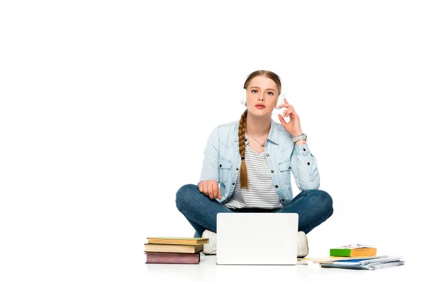 Girl sitting on floor in headphones near laptop, books and copybooks isolated on white — Stock Photo