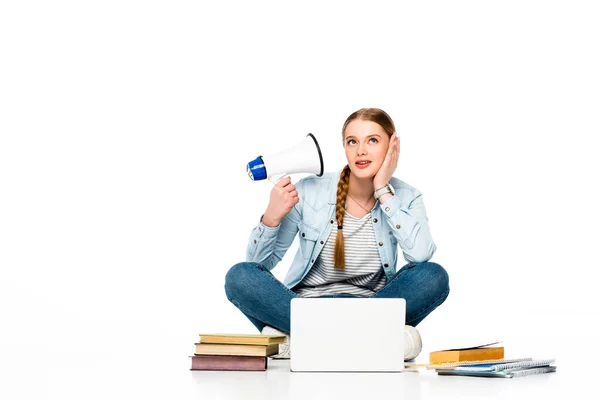 Girl sitting on floor with loudspeaker near laptop, books and copybooks isolated on white — Stock Photo