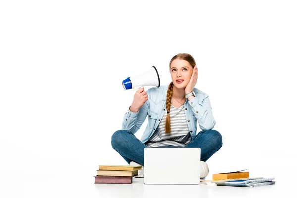 Niña sentada en el suelo con altavoz cerca de la computadora portátil, libros y copybooks aislados en blanco - foto de stock