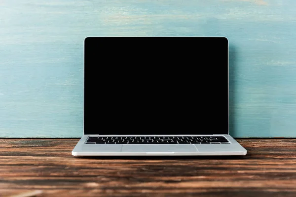 Laptop com tela em branco na mesa de madeira perto da parede azul — Fotografia de Stock