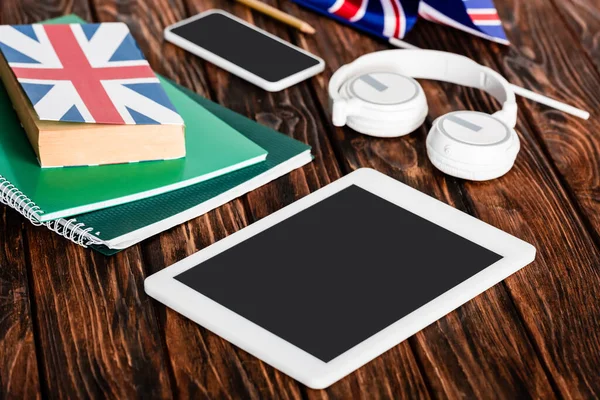 Gadgets perto de livros e livro com bandeira do Reino Unido na mesa de madeira — Fotografia de Stock