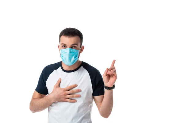 Man in medical mask touching chest and pointing with finger isolated on white — Stock Photo