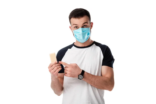 Man in medical mask pointing with finger at soap bar isolated on white — Stock Photo
