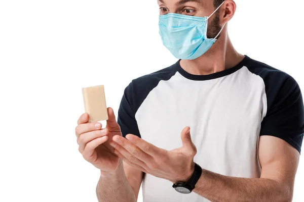 Man in medical mask looking at soap bar isolated on white — Stock Photo