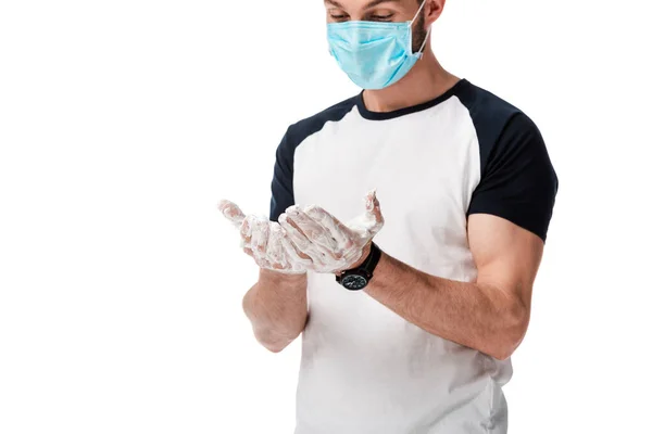 Man in medical mask looking at soapy hands isolated on white — Stock Photo
