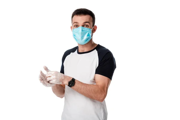 Человек в медицинской маске моет руки, стоя изолированным на белом — стоковое фото