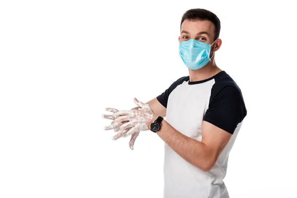 Людина в медичній масці миє руки і стоїть ізольовано на білому — стокове фото