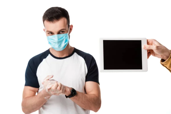 Homem em máscara médica lavar as mãos perto de tablet digital com tela em branco isolado em branco — Fotografia de Stock