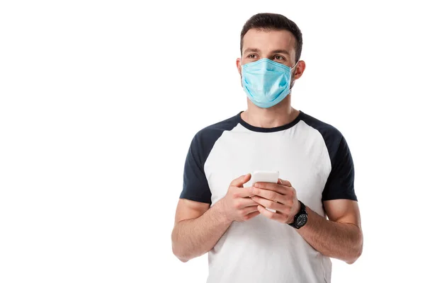 Hombre en máscara médica celebración de teléfono inteligente aislado en blanco - foto de stock